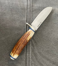 Load image into Gallery viewer, A hunting knife with a stainless steel blade and a handle made of deer antler, featuring blue and red G10 spacers. The knife is placed on a gray surface.